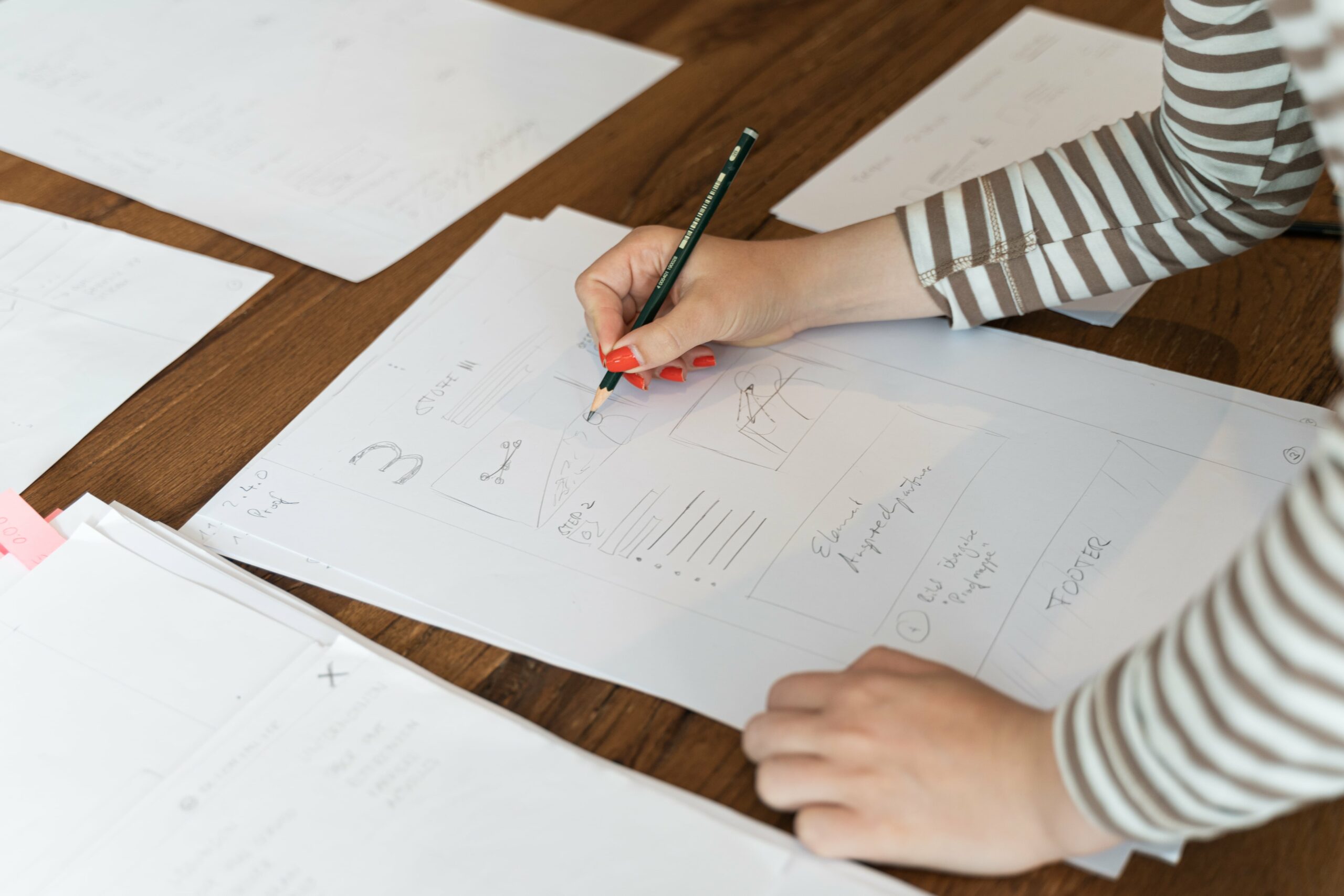 Eine Person zeichnet mit einem Bleistift Entwürfe für den Brand Refresh auf Papier.